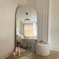 a mirror sitting on top of a wooden floor next to a white couch and pillows