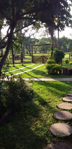 a garden with stepping stones in the grass and trees on either side, surrounded by greenery