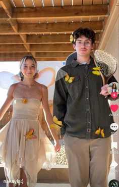 a young man and woman dressed up in fairy costumes standing next to each other holding hands