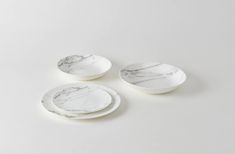 three white marble plates sitting on top of each other