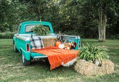 an old pickup truck with hay bales and pumpkins in the bed is parked on grass