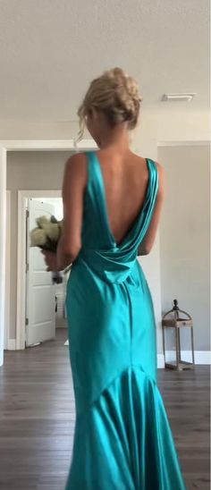 a woman in a blue dress is walking towards the camera with her back to the camera