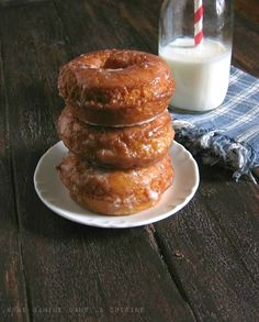 three donuts stacked on top of each other with a glass of milk in the background