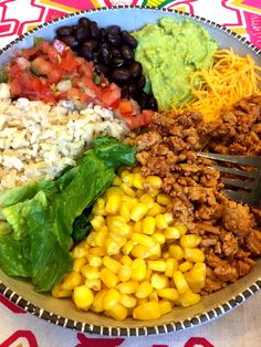 a plate filled with different types of food on top of a colorful table cloth next to a fork