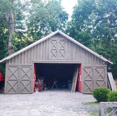 a garage with two doors open in front of trees