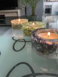 three candles sitting on top of a glass table