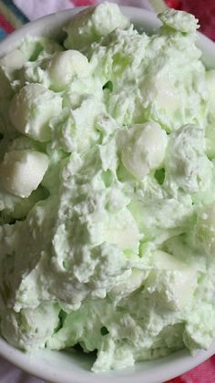 a white bowl filled with cucumber salad on top of a colorful table cloth