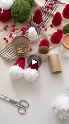 yarn balls, scissors and other crafting supplies on a white table with red pom - poms