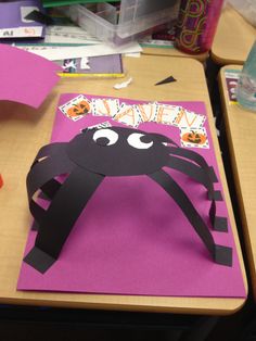 a paper cut out of a spider on top of a pink table with other crafting supplies