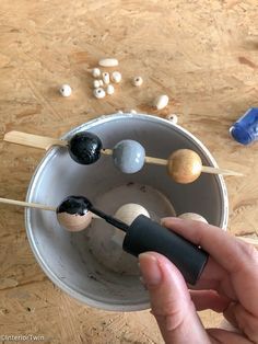 a person holding an object in their hand with other objects on the table behind them