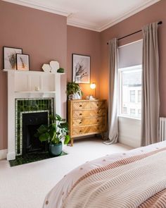 a bedroom with a fireplace, dresser and window in the corner next to a bed