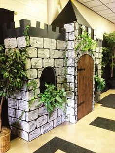 a castle made out of cardboard with plants growing on the wall and door to it