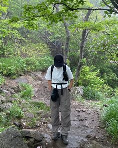 a person with a backpack standing on a path in the woods