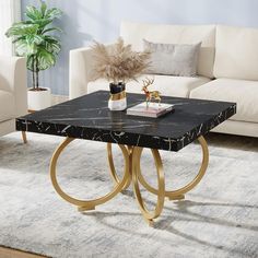 a black marble coffee table with gold metal legs in a living room setting next to a white couch