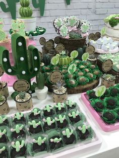 a table topped with lots of desserts covered in green frosting and cactus decorations