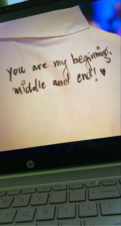 a laptop computer sitting on top of a desk with a message written on the screen