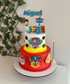 a three tiered birthday cake with cartoon characters on the top and candles in the middle