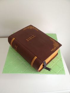 a cake made to look like a bible on top of a green book cover with gold lettering