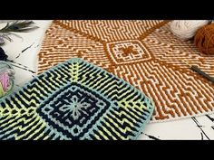 two crocheted rugs sitting on top of a table next to yarn and knitting needles