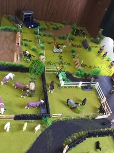 a toy farm with horses and other animals on the ground next to a fenced in area