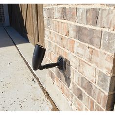 a black pipe is attached to the side of a brick building with a door in the background