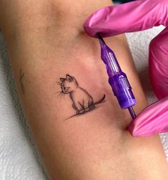 a cat tattoo on the thigh with a syringe in it's hand