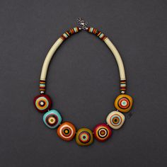 a multicolored necklace is displayed on a gray surface