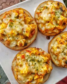 four pieces of bread with cheese and other toppings on them sitting on a white plate