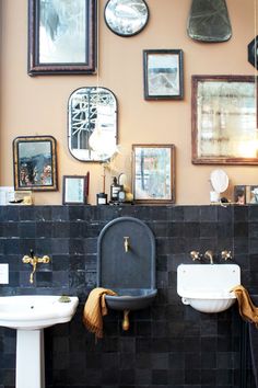 a bathroom with two sinks, mirrors and pictures on the wall