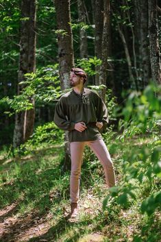 a man is standing in the woods with his hands on his hips and wearing a hat