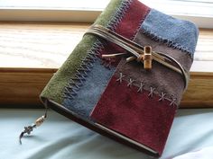 a small notebook covered in different colored towels sitting on a window sill next to a window