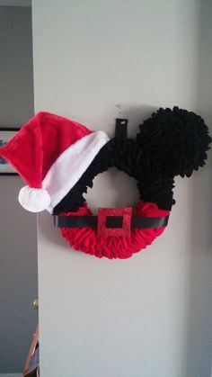 a mickey mouse wreath hanging on the side of a wall with a santa claus hat