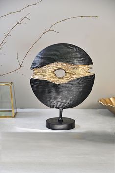 a black and gold sculpture sitting on top of a white table next to a vase