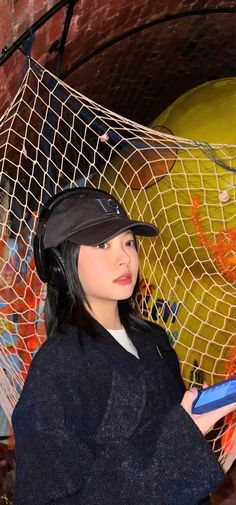 a woman wearing a hat and holding an umbrella in front of a wall with graffiti on it