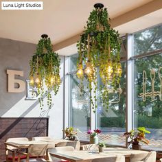 a dining room table and chairs with plants hanging from the chandelier above them