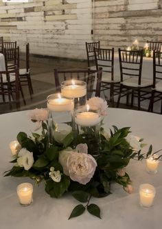 a centerpiece with candles and flowers on a white table cloth at a wedding reception