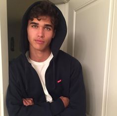 a young man wearing a black hoodie with his arms crossed