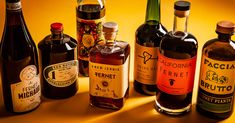 an assortment of different types of wine bottles on a yellow background with shadows from the bottle