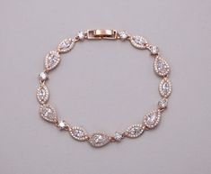 "Add bold elegance with these exquisitely designed open framed cubic zirconia teardrop wedding bracelet. Bracelet measures 7\" long. Matching (optional) necklace and earrings feature a pear top portion, a halo marquise piece ending in a double dangling tear drop pear accents set in brilliant rose gold. Matching necklace measures 16\" and is adjustable up to 18\" long. Available in silver, gold or rose gold finish. All jewelry features high quality electroplating that does not fade or chip and is Formal Teardrop Cubic Zirconia Bracelet, Formal Cubic Zirconia Teardrop Bracelets, Pear-shaped Silver Bracelet For Weddings, Elegant Pear-shaped Bracelets For Wedding, Elegant Pear-shaped Bracelet For Wedding, Gold Wedding Bracelet, Rose Gold Bracelet Set, Silver Wedding Bracelet, Rose Gold Jewelry Set