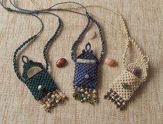 three necklaces with beads and bead work hanging on a piece of cloth covered table