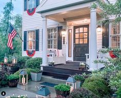 a white house with an american flag on it's front porch and flags hanging from the windows