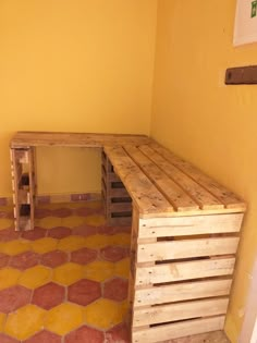 a bench made out of wooden pallets in a room with yellow walls and flooring