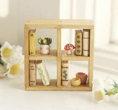 a small wooden box with books and plants in it sitting on a table next to flowers