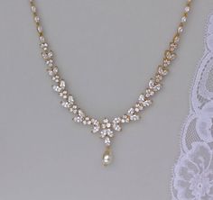 the necklace is adorned with white pearls and gold chains, along with a pearl droplet