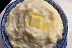 a bowl filled with mashed potatoes and butter on top of a white countertop