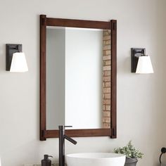 a bathroom sink sitting under a mirror next to a wall mounted faucet and lights