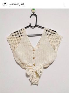 a crocheted sweater hanging on a hanger