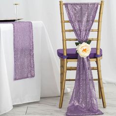 a purple chair with a white flower on it next to a table set for a wedding