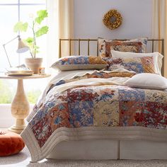 a bed in a room with a large window and pillows on top of the bedspread