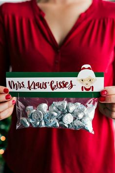 a woman holding a bag of hers kisses in front of a christmas tree with santa clause on it